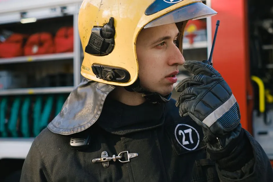 Firefighter using a handheld radio transceiver, illustrative photo